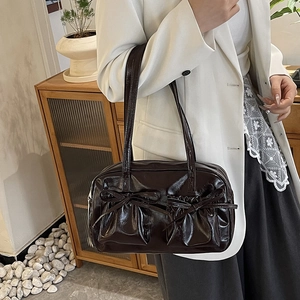 Détail d'un sac cabas en cuir brillant marron foncé avec d'élégants nœuds décoratifs