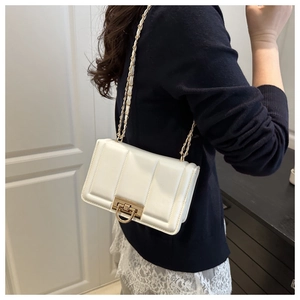 Détail du sac à bandoulière blanc matelassé avec boucle dorée sur le mannequin
