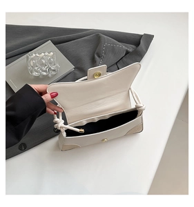 Detail view of cream white shoulder bag showing magnetic closure and interior space