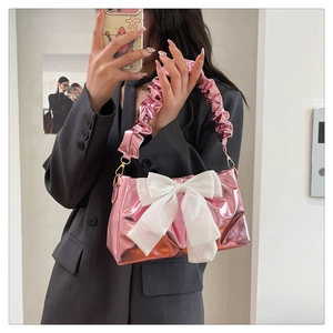 Detailed shot of pink metallic bag with large white silk bow and pleated handle