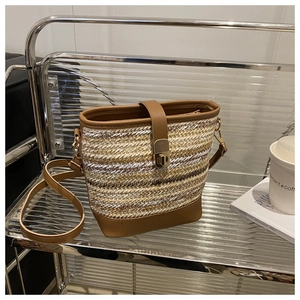 Detail of woven straw bucket bag with brown leather trim and golden metal clasp