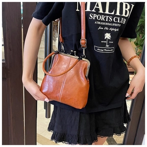 Close-up of caramel brown retro kiss-lock bag with metal ring handle and fine stitching