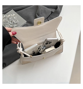 Detail of off-white shoulder bag interior showing daily essentials and wave-shaped flap