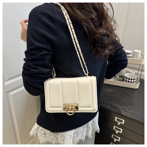 Détail d'un sac bandoulière crème avec boucle dorée en D et bandoulière en chaîne