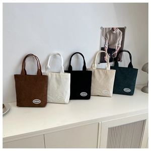 Dettaglio di borse tote in velluto a coste in cinque colori tra cui marrone, bianco e nero