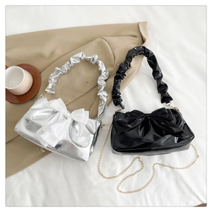 Detailed view of handbags with oversized bow accents and metallic chain straps