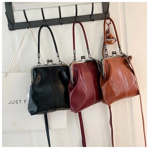 Three retro doctor style bags in black, burgundy, and tan leather on a metal display rack