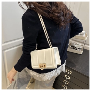 Sac bandoulière blanc matelassé avec chaîne dorée porté par un mannequin chic