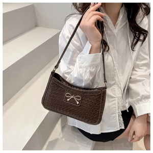 Détail du sac porté épaule marron foncé à texture crocodile et boucle nœud doré élégant