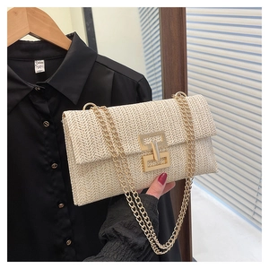 Detail of light beige straw crossbody bag with golden interlocking clasp and chain strap
