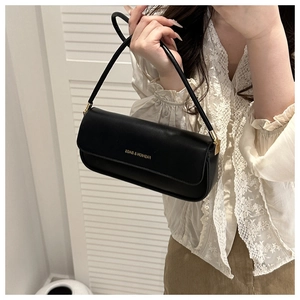 Detail view of black minimalist leather baguette bag with golden hardware and chic strap