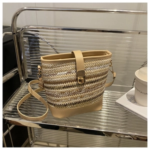 Detail view of woven bucket bag featuring tri-color fibers and golden turn-lock closure