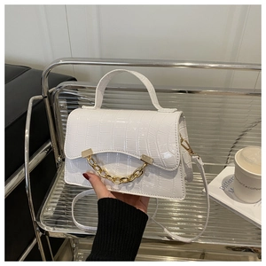 Close-up of white crocodile pattern handbag with gold chain detail and handle