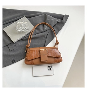 Detail of vintage brown crocodile embossed bag with wide strap and gold metal buckle
