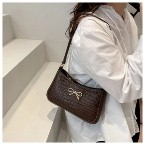 Détail du sac à bandoulière marron foncé tressé avec boucle papillon dorée élégante