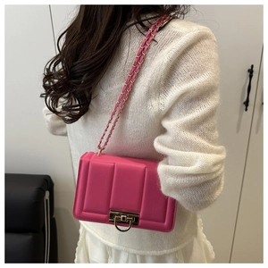 Détail du sac à bandoulière rose vif avec texture matelassée et chaîne dorée