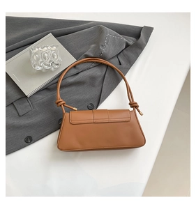 Detail view of brown faux leather baguette bag with knotted shoulder strap on blazer