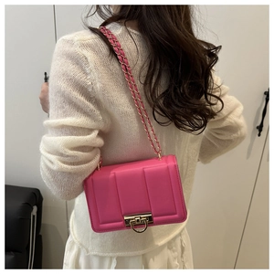 Détail du sac bandoulière fuchsia matelassé avec boucle dorée porté par un modèle