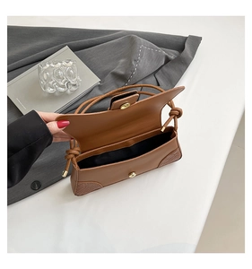 Detail of brown faux leather handbag with crocodile texture and magnetic closure