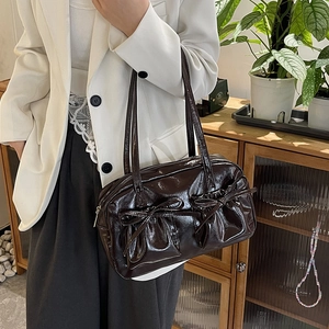 Vue latérale du sac fourre-tout en cuir verni marron foncé avec deux nœuds décoratifs