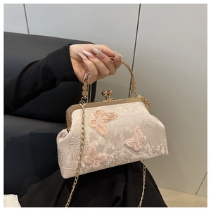 Détail du sac coquillage crème avec broderie papillon rose et poignée dorée