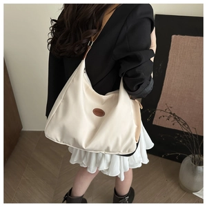 Shoulder bag detail showing cream fabric with brown leather strap and fashion label