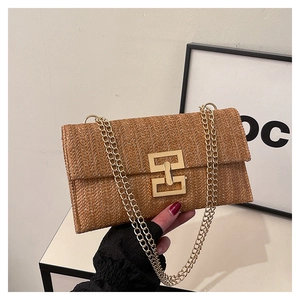 Detail of woven straw handbag featuring V-pattern texture and gold metal chain strap