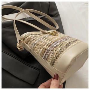 Detail of cream woven bucket bag showing natural texture and gold twist lock closure