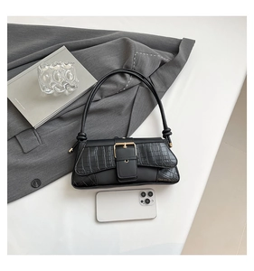 Detail of black crocodile texture bag with gold square buckle and phone for scale