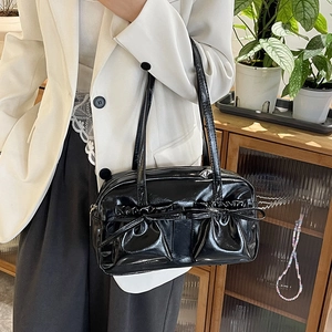 Détail d'un sac cabas en cuir verni noir avec nœud décoratif et finition brillante