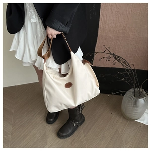 Detail of minimalist cream tote bag with brown leather accents and fashion logo patch