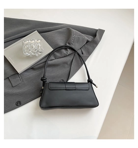 Detail view of black crocodile pattern baguette bag with stylish knot strap and metal buckle