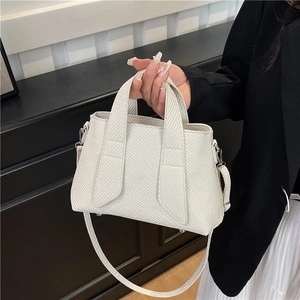 Chic cream striped tote bag with woven texture shown in a stylish hand-carried pose