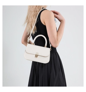 White faux leather flap handbag with gold twist lock shown on model with black dress