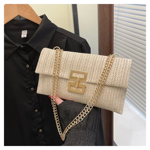 Detailed shot of straw woven crossbody bag with gold metal clasp and chain strap
