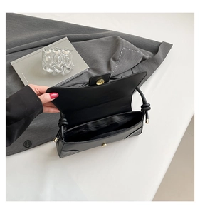 Detail of black faux crocodile skin shoulder bag showing magnetic closure and interior space