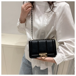 Petit sac bandoulière noir matelassé avec chaîne dorée porté par un mannequin élégant