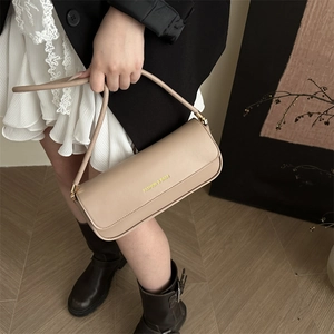 Chic beige baguette underarm bag with gold lettering shown in a stylish fashion outfit