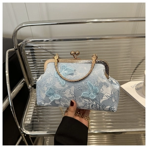Détail du sac coquille bleu clair avec broderie papillon et poignée métallique