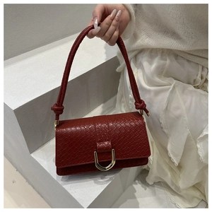 Detail der ziegelroten quadratischen Tasche mit geflochtenem Griff und Metallschnalle