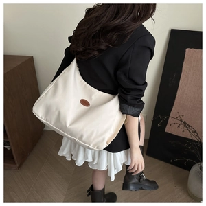 Chic cream nylon shoulder bag with leather FASHION patch shown on model for daily use