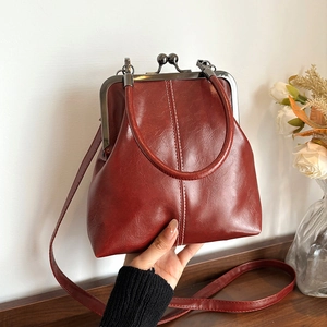 Retro burgundy kiss-lock handbag with round metal handle and adjustable leather shoulder strap