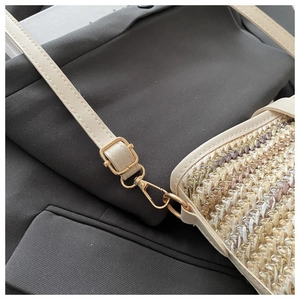 Detailed close-up of beige woven texture and gold metal hardware on the bucket bag