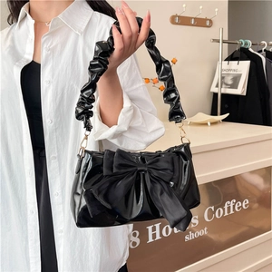 Fashionable black patent leather crossbody bag with oversized bow and ruched shoulder strap
