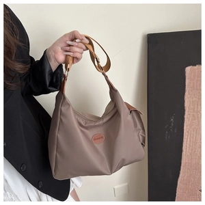 Detailed close-up of taupe nylon shoulder bag featuring a leather Fashion logo patch