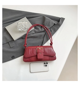 Macro shot of red croc-embossed leather underarm bag with elegant gold square buckle