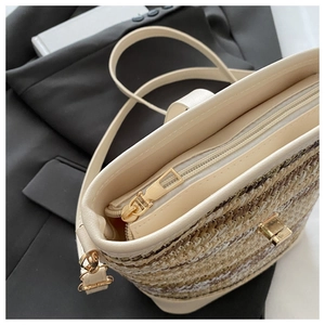 Detail of woven straw bucket bag with gold hardware and white faux leather strap