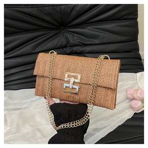 Close-up of brown straw crossbody bag with golden chain strap and metal lock
