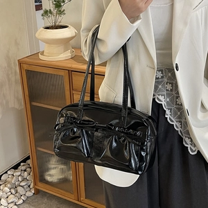 Détail du sac cabas noir brillant avec des plis froncés et des nœuds décoratifs élégants