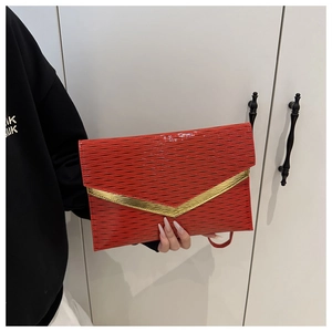 Detail of red envelope clutch featuring wavy embossed texture and gold V-shaped metal hardware